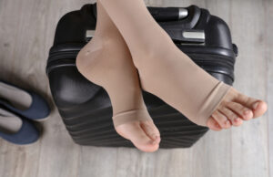 Woman,Wears,Compression,Socks,Propped,Feet,On,Travel,Bag.