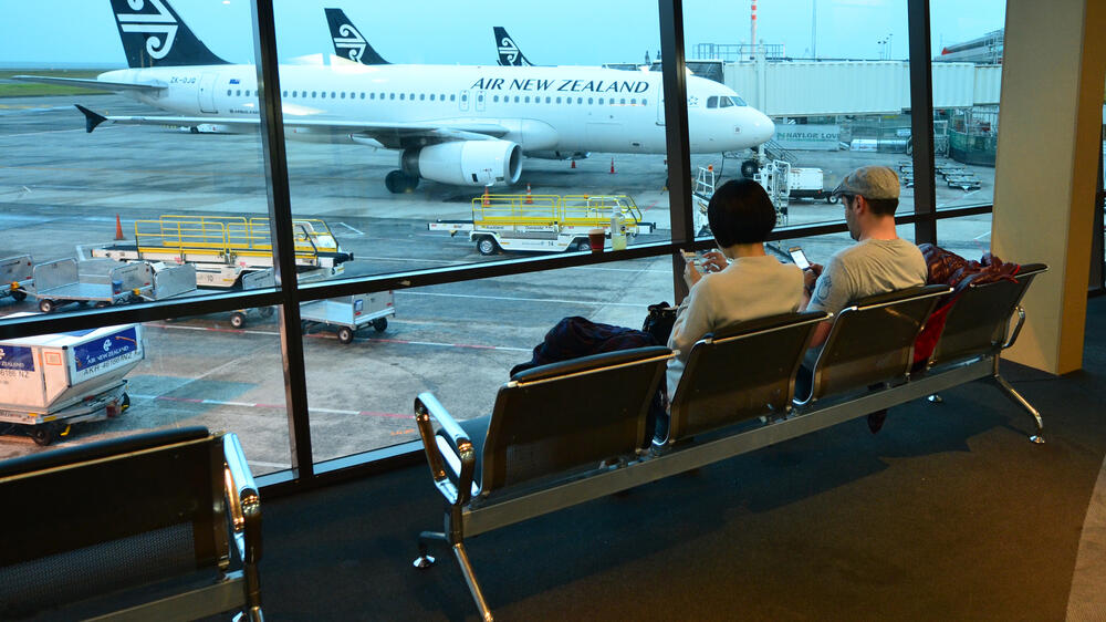 Fly,Long,Distance,People,On,Phones,Sitting,Looking,Out,At,Air,NewZealand,Plane.